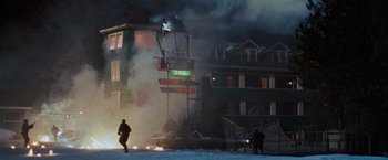 Movie still from “The Long Kiss Goodnight” (1996), directed by Renny Harlin – A man standing in front of a building on fire; Extreme Wide shot, High angle