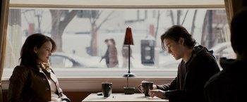 Movie still from “The Lookout” (2007), directed by Scott Frank – A woman sitting at a table with two cups of coffee; Medium shot, Over the shoulder angle