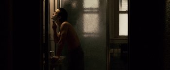Movie still from “The Lookout” (2007), directed by Scott Frank – A man is standing in a bathroom drinking a cup of coffee; Medium shot, Over the shoulder angle