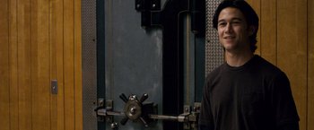 Movie still from “The Lookout” (2007), directed by Scott Frank – A man standing in front of a large metal door; Medium shot, Over the shoulder angle