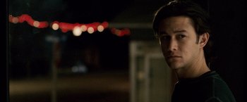 Movie still from “The Lookout” (2007), directed by Scott Frank – A man standing in the dark with lights in the background; Close Up shot, Over the shoulder angle
