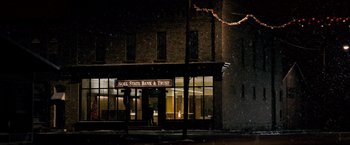 Movie still from “The Lookout” (2007), directed by Scott Frank – Two people standing outside of a bank at night in the snow; Extreme Wide shot, High angle