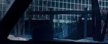 Movie still from “The Lookout” (2007), directed by Scott Frank – A man in a white coat standing in front of a building; Extreme Wide shot, Low angle