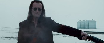 Movie still from “The Lookout” (2007), directed by Scott Frank – A man with long black hair wearing sunglasses and a black jacket; Medium shot, Low angle