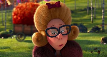 Movie still from “The Lorax” (2012), directed by Chris Renaud – A woman with big blonde hair wearing glasses and a red bow tie; Close Up shot, Over the shoulder angle