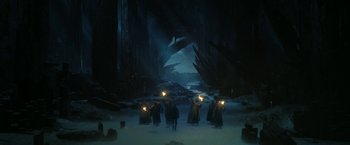 Movie still from “The Lord of the Rings: The Rings of Power” (2022), created by Patrick McKay – A group of people walking through a cave with lights on; Extreme Wide shot, High angle