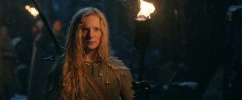 Movie still from “The Lord of the Rings: The Rings of Power” (2022), created by Patrick McKay – A woman holding a burning torch in a dark forest; Close Up shot, Low angle