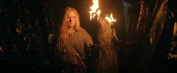 Movie still from “The Lord of the Rings: The Rings of Power” (2022), created by Patrick McKay – Two women are holding torches in a dark forest; Medium shot, Low angle