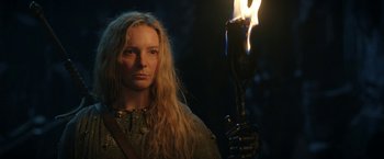 Movie still from “The Lord of the Rings: The Rings of Power” (2022), created by Patrick McKay – A woman with long blonde hair holding a burning torch; Close Up shot, Low angle