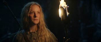 Movie still from “The Lord of the Rings: The Rings of Power” (2022), created by Patrick McKay – A woman standing in front of a flame; Close Up shot, Low angle