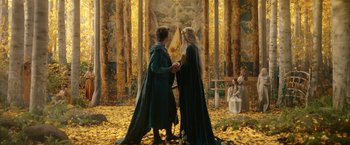 Movie still from “The Lord of the Rings: The Rings of Power” (2022), created by Patrick McKay – Two people dressed in medieval garb holding hands in a forest; Wide shot, Low angle