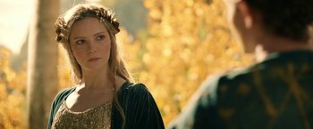 Movie still from “The Lord of the Rings: The Rings of Power” (2022), created by Patrick McKay – A beautiful young lady with long blonde hair wearing a flower crown; Close Up shot, Over the shoulder angle