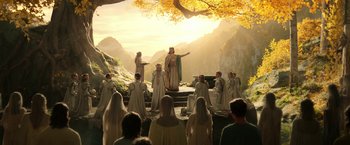 Movie still from “The Lord of the Rings: The Rings of Power” (2022), created by Patrick McKay – A group of people are gathered around a stage; Wide shot, Low angle