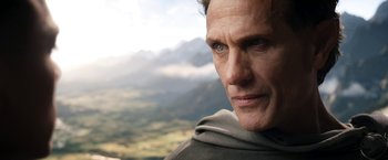 Movie still from “The Lord of the Rings: The Rings of Power” (2022), created by Patrick McKay – A man's face with mountains in the background; Close Up shot, Low angle