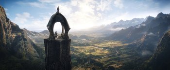 Movie still from “The Lord of the Rings: The Rings of Power” (2022), created by Patrick McKay – An aerial view of a valley with a person sitting on top of it; Extreme Wide shot, Low angle