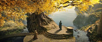 Movie still from “The Lord of the Rings: The Rings of Power” (2022), created by Patrick McKay – Two people standing on steps next to a tree; Extreme Wide shot, High angle