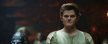 Movie still from “The Lord of the Rings: The Rings of Power” (2022), created by Patrick McKay – A man in a green shirt is standing in front of a woman; Close Up shot, Low angle