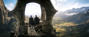 Movie still from “The Lord of the Rings: The Rings of Power” (2022), created by Patrick McKay – Two people are standing on a platform looking out over a valley; Wide shot, Low angle
