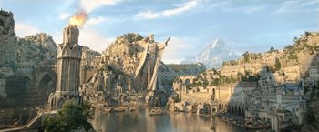 Movie still from “The Lord of the Rings: The Rings of Power” (2022), created by Patrick McKay – A large statue of a man standing on top of a mountain; Extreme Wide shot, Low angle