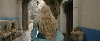 Movie still from “The Lord of the Rings: The Rings of Power” (2022), created by Patrick McKay – A woman walking down a street with long blonde hair; Medium shot, Over the shoulder angle