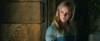 Movie still from “The Lord of the Rings: The Rings of Power” (2022), created by Patrick McKay – A beautiful young lady with blue eyes standing next to a stone wall; Close Up shot, Over the shoulder angle
