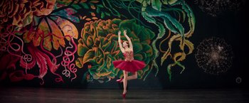 Movie still from “Red Sparrow” (2018), directed by Francis Lawrence – A woman in a red dress is doing a dance move; Wide shot, Low angle