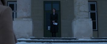 Movie still from “Red Sparrow” (2018), directed by Francis Lawrence – A woman standing on the steps of a building holding an envelope; Wide shot, Low angle