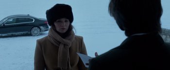 Movie still from “Red Sparrow” (2018), directed by Francis Lawrence – A woman wearing a hat and scarf holding a piece of paper in front of a man; Close Up shot, Over the shoulder angle
