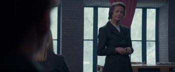 Movie still from “Red Sparrow” (2018), directed by Francis Lawrence – A woman in a suit standing in front of a window; Medium shot, Over the shoulder angle