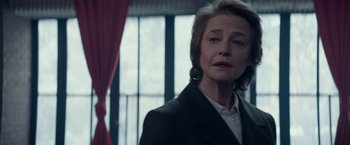 Movie still from “Red Sparrow” (2018), directed by Francis Lawrence – An older woman wearing a suit and looking at the camera; Close Up shot, Over the shoulder angle