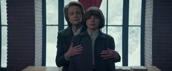 Movie still from “Red Sparrow” (2018), directed by Francis Lawrence – A woman standing next to a young boy in front of a window; Medium shot, Low angle