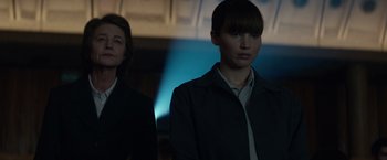 Movie still from “Red Sparrow” (2018), directed by Francis Lawrence – Two women standing next to each other in front of a wall; Medium shot, Low angle