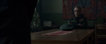Movie still from “Red Sparrow” (2018), directed by Francis Lawrence – A green hat sitting on top of a wooden table; Medium shot, Over the shoulder angle