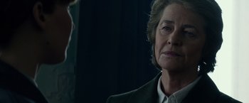 Movie still from “Red Sparrow” (2018), directed by Francis Lawrence – An older woman in a green jacket looking at the camera; Close Up shot, Over the shoulder angle