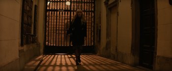 Movie still from “Red Sparrow” (2018), directed by Francis Lawrence – A woman walking down a street in a dark place; Wide shot, Low angle