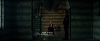 Movie still from “Red Sparrow” (2018), directed by Francis Lawrence – A woman sitting at a table in a room; Wide shot, High angle