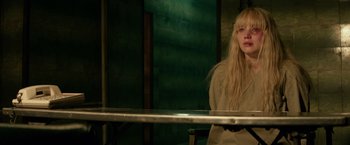 Movie still from “Red Sparrow” (2018), directed by Francis Lawrence – A woman sitting in front of a metal table; Medium shot, Over the shoulder angle