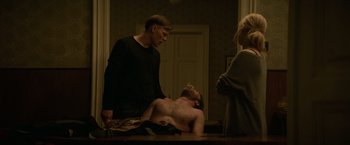 Movie still from “Red Sparrow” (2018), directed by Francis Lawrence – Two men and a woman standing in front of a table; Medium shot, Over the shoulder angle