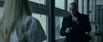 Movie still from “Red Sparrow” (2018), directed by Francis Lawrence – A man standing in front of a window holding a cell phone; Medium shot, Over the shoulder angle