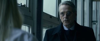 Movie still from “Red Sparrow” (2018), directed by Francis Lawrence – An older man wearing glasses and a black coat; Close Up shot, Over the shoulder angle
