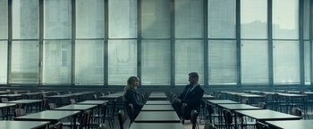 Movie still from “Red Sparrow” (2018), directed by Francis Lawrence – A man and a woman sitting at a table in a room; Wide shot, High angle