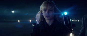 Movie still from “Red Sparrow” (2018), directed by Francis Lawrence – A woman with long blonde hair standing in the dark; Close Up shot, Over the shoulder angle