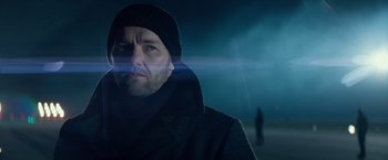 Movie still from “Red Sparrow” (2018), directed by Francis Lawrence – A man wearing a black coat and a black hat; Close Up shot, Low angle