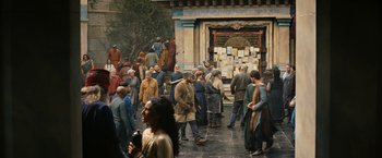 Movie still from “The Lord of the Rings: The Rings of Power” (2022), created by Patrick McKay – A group of people standing in front of a building; Wide shot, High angle