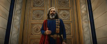 Movie still from “The Lord of the Rings: The Rings of Power” (2022), created by Patrick McKay – A bearded man in a blue and red costume; Medium shot, Low angle