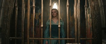 Movie still from “The Lord of the Rings: The Rings of Power” (2022), created by Patrick McKay – A woman standing behind bars in front of a stained glass window; Medium shot, Low angle