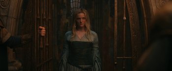 Movie still from “The Lord of the Rings: The Rings of Power” (2022), created by Patrick McKay – A woman standing in front of a door wearing a dress; Medium shot, Low angle