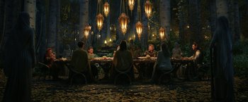 Movie still from “The Lord of the Rings: The Rings of Power” (2022), created by Patrick McKay – A group of people sitting at a table in the woods; Wide shot, High angle