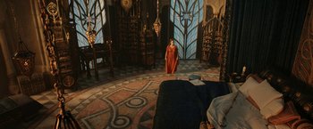 Movie still from “The Lord of the Rings: The Rings of Power” (2022), created by Patrick McKay – A woman in a red dress standing in front of a bed in a room; Extreme Wide shot, High angle