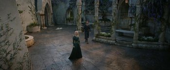 Movie still from “The Lord of the Rings: The Rings of Power” (2022), created by Patrick McKay – A man and a woman in medieval garb walk through a courtyard; Wide shot, High angle